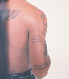 the back of a man with tattoos on his upper half and shoulder, looking down