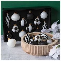 black and white ornaments in a wooden bowl next to a box with one ornament on it