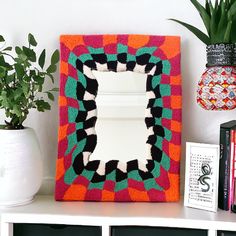 a white shelf topped with a mirror next to a potted plant and other items