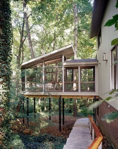 a house in the woods with lots of windows on it's roof and deck