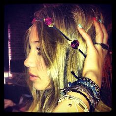 a woman with long blonde hair and bracelets on her head is holding something up to her ear