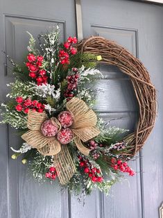 a wreath with red berries and greenery hangs on the front door