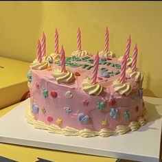 a birthday cake with pink frosting and lit candles