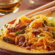 a wooden plate topped with noodles and meat