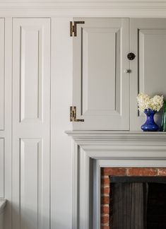 a fireplace with white cabinets and a blue vase