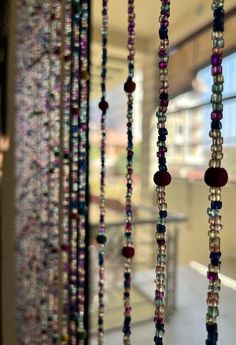 several beads are hanging from the ceiling in front of a glass door with a window behind them