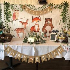 a baby shower party with woodland animals on the wall and welcome banner over the table