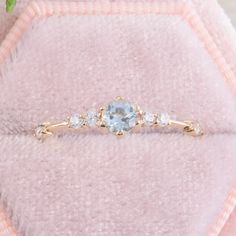 a close up of a ring on top of a pink blanket with flowers in the background