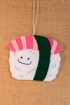 a felt ornament with a sushi on it's face hanging from a string