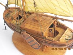 a wooden model boat with yellow sails