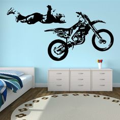 a bedroom with a bed, dresser and wall decal depicting two people on motorbikes