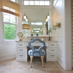 a blue chair sitting in front of a bathroom mirror next to a sink and window