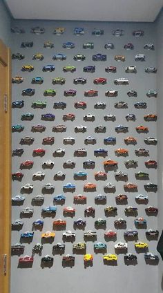 a room filled with lots of toy cars on top of a white wall next to a door