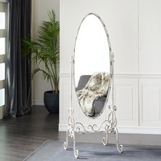 a mirror sitting on top of a wooden floor next to a chair and potted plant