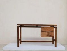 a wooden table with two drawers on top and one drawer at the bottom, sitting on a white platform