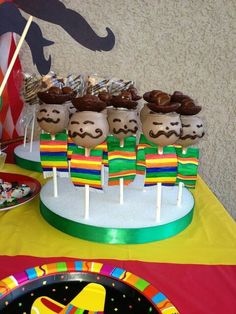 a table topped with cake pops covered in frosting and mustaches on top of them