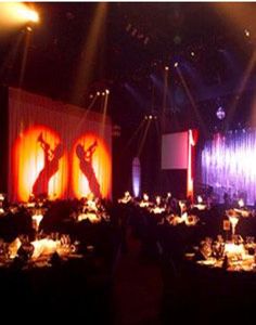 an empty banquet hall is lit up with red and purple lighting, while the stage has been set for a show