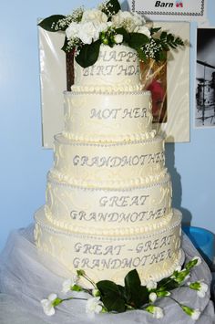 a white wedding cake with flowers on the top and writing on the bottom is sitting on a table