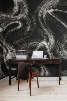 a desk with a laptop on it in front of a black and white wall mural