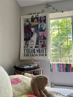 a teddy bear sitting in front of a window next to a book shelf with books on it