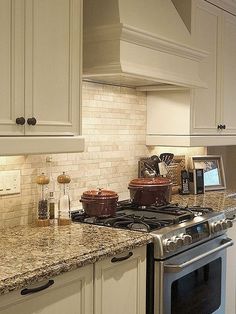 a kitchen with white cabinets and granite counter tops, an oven and stove top in the center