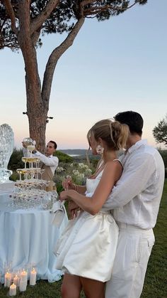 two people standing next to each other in front of a table with cake on it