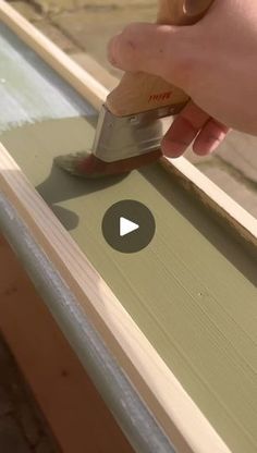 a person using a paint roller to finish a piece of wood on a window sill