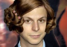 a man in a suit and tie with curly hair wearing a flower in his hair