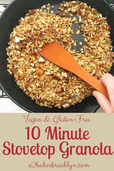 a pan filled with granola on top of a stove next to a wooden spoon