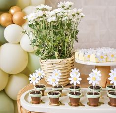 a table topped with cupcakes and flowers next to a basket filled with daisies