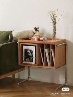 a cat laying on top of a wooden shelf next to a green chair and bookshelf