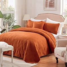 a bed with an orange comforter and pillows