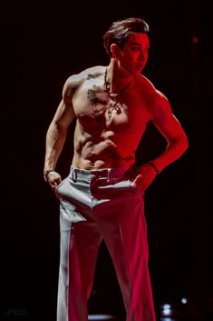 a shirtless man standing in the dark with his hands on his hips and one hand on his hip