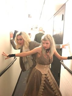 two women dressed in costumes are standing on the stairs with their arms spread out and looking at the camera