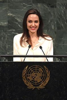 a woman standing at a podium in front of a microphone