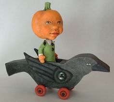 a small figurine sitting on top of a black bird with an orange head