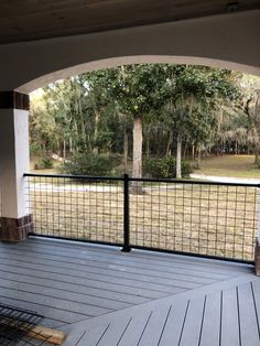 an outdoor deck with black iron railing and wood flooring, overlooking a grassy area