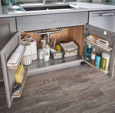 an open cabinet in a kitchen with items on the shelves and under it's sink