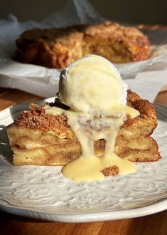 a piece of cake with ice cream on top is sitting on a plate next to a pastry