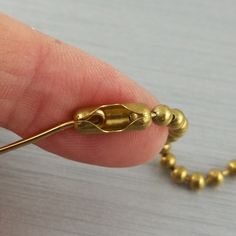 a tiny gold bead is being held by a person's finger