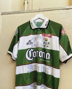 a green and white polo shirt hanging on a wall with the word corona printed on it