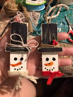 two snowmen made out of popsicle sticks are shown in the palm of someone's hand