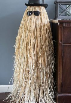 a hat and sunglasses are on top of a long, shaggy wig in front of a dresser