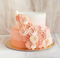 a three layer cake with pink and white frosting flowers on the top, sitting on a gold plate