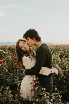 a man and woman kissing in a field of flowers