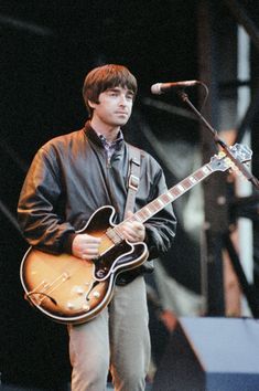 a young man playing an electric guitar while standing in front of a microphone on stage