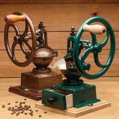 an old fashioned coffee grinder sitting on top of a wooden table next to seeds