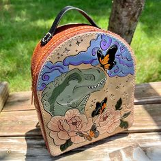 "Butterfly Kisses" handcrafted, 100% genuine leather backpack.  🦋Crafted from start to finish by me using high quality materials and slow, meticulous, timeless skill.  🦋This is a one of a kind artwork, featuring my original drawing that I have tooled (leather carved) then painted into vegetable tanned leather.  🦋The body of the bag has been crafted in gorgeous whiskey-hued oil tan leather and hand dyed and oiled vegetable tan. The inside features a soft, dusty pink pig suede partial lining (to reduce bulk and weight, the inside bottom and inside front have been lined, the inside back and top are unlined, revealing the soft brown underside of the main leather). No interior pockets 🦋12" nylone zipper opening (color = peach/coral) 🦋Brass buckles and rings 🦋Adjustable, belt style, all ma Leather Backpack With Case For Everyday Use, Painted Leather Backpack, Handmade Leather Backpack For Daily Use, Handmade Leather Standard Backpack, Hand Painted Backpack, Hand Painted Leather Tote Shoulder Bag, Painted Backpack, Hand Painted Brown Satchel Shoulder Bag, Brown Hand Painted Satchel Shoulder Bag