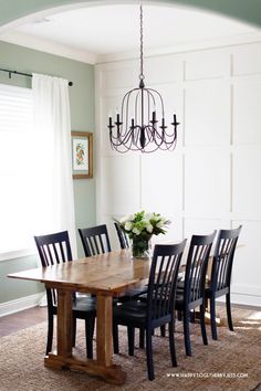 a dining room table with black chairs and a chandelier hanging from the ceiling