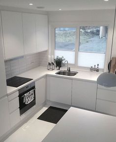 a white kitchen with black and white flooring on the counter top, sink, oven and window